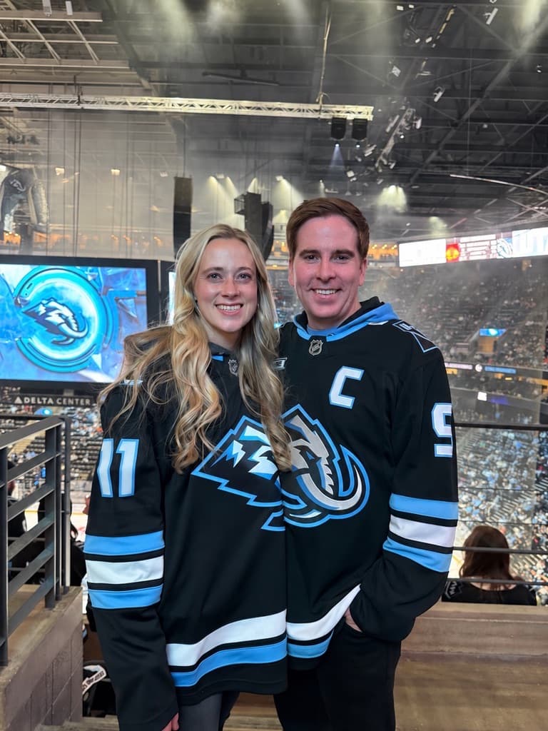 Peter and his wife in Utah hockey jerseys at a game
